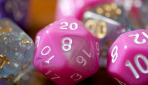close up of polyhedral dice. some are pink and some are sparkly